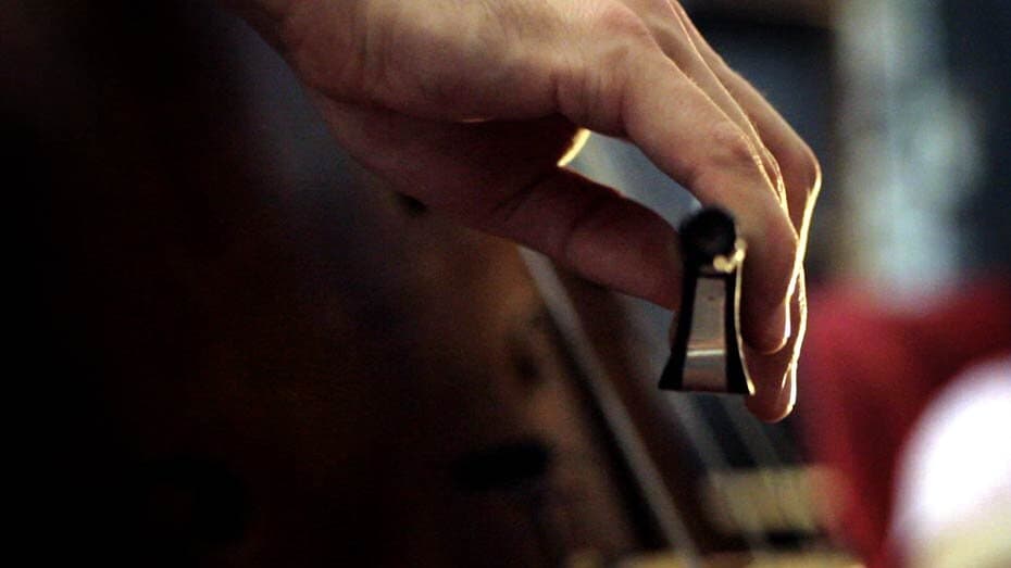 A musician playing an acoustic bass, close-up on the bow